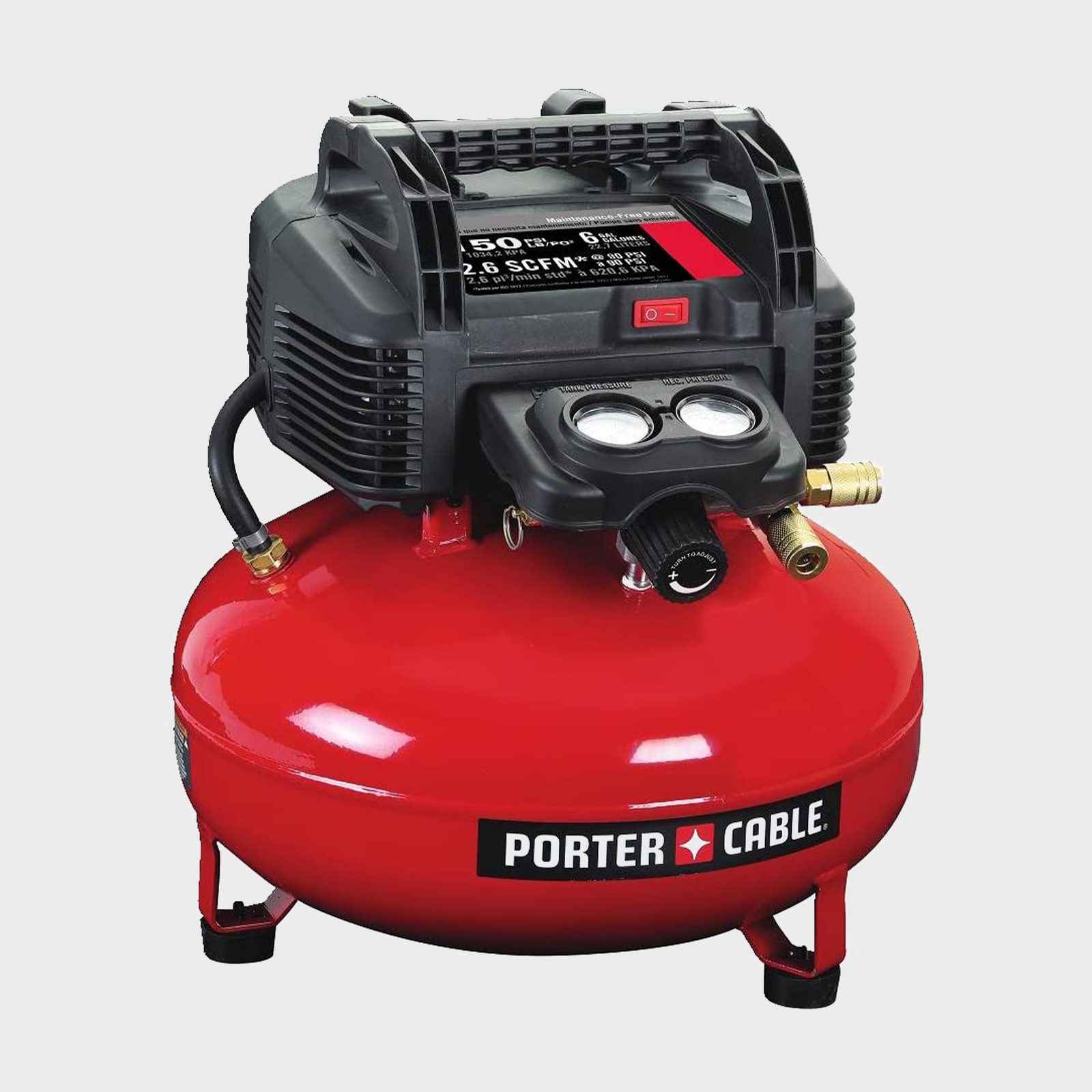 A red air compressor with a black motor fills an attached tank, providing compressed air for various tools in a workshop environment.