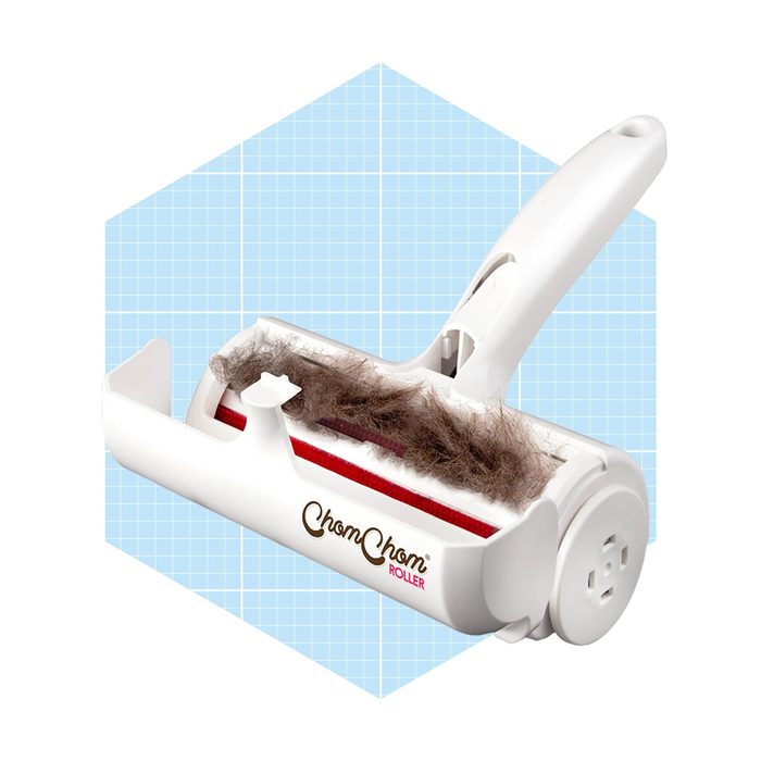 A lint roller collects pet hair using a sticky surface, featuring a white handle and a visible accumulation of fur, set against a light blue grid background.