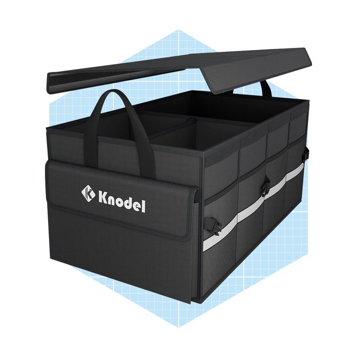 A rectangular storage bin with a lid is open, revealing multiple compartments inside. It