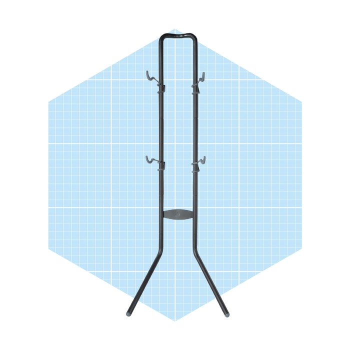 A black coat rack stands upright, featuring hooks at the top and a circular base, against a light blue grid-patterned background.