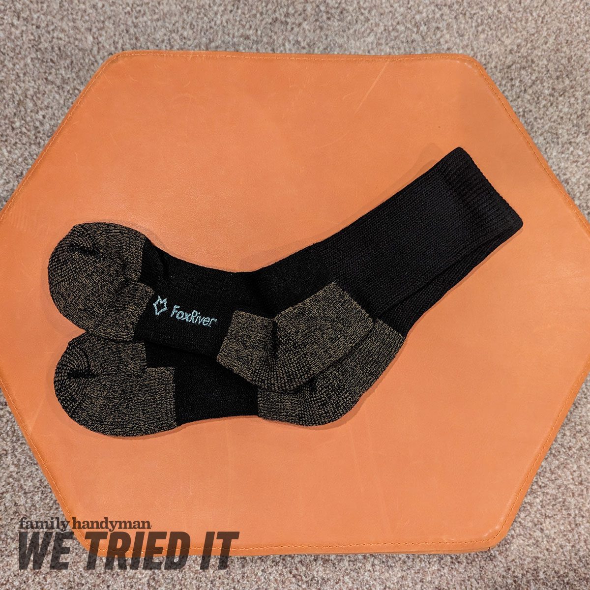 Black and brown socks lie flat on a brown hexagonal surface, surrounded by a gray textured background, appearing ready for use or display.