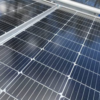 Wind solar panels collect sunlight and convert it into electricity, positioned on a surface under bright lighting, with a few scattered dust particles visible.