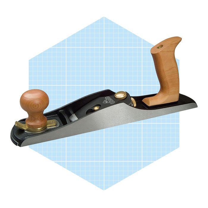 A woodworking hand plane rests horizontally with wooden handles, reflecting its purpose for smoothing surfaces, set against a light blue, grid-patterned background.