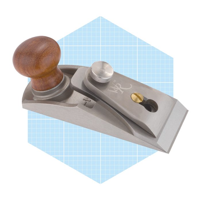 A metal hand plane with a wooden handle rests on a light blue grid background, showcasing its precision engineering and design for woodworking tasks.