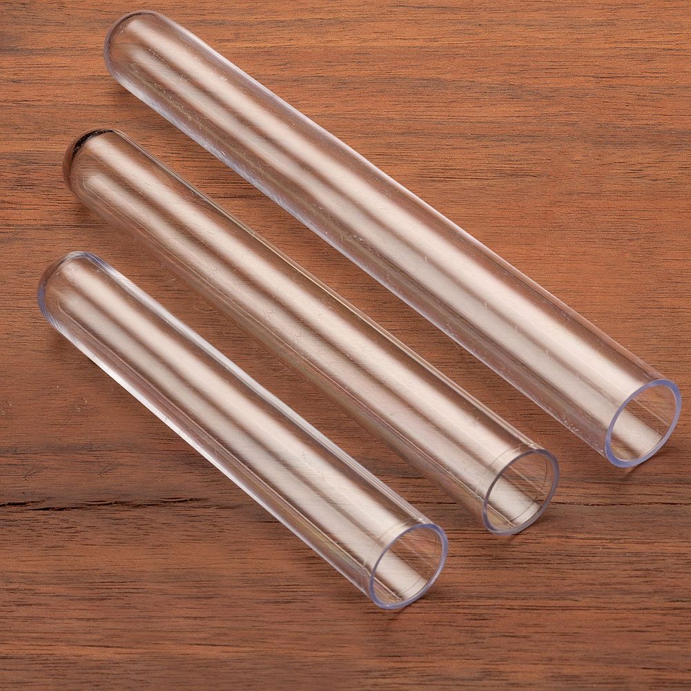 Three transparent glass tubes of varying lengths are arranged parallel on a wooden surface, showcasing their smooth surfaces and open ends.