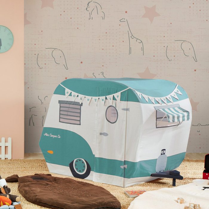 A teal-and-white play tent resembling a camper sits on a textured floor; background features illustrated animals and stars, creating a playful atmosphere.