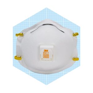 A white N95 mask with yellow straps is positioned centrally against a light blue grid background, designed for respiratory protection in various environments.