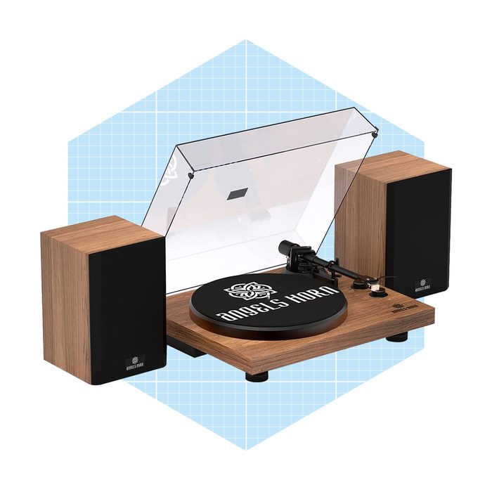 A turntable with a transparent cover spins a black record, flanked by two wooden speakers, set against a light blue grid background.