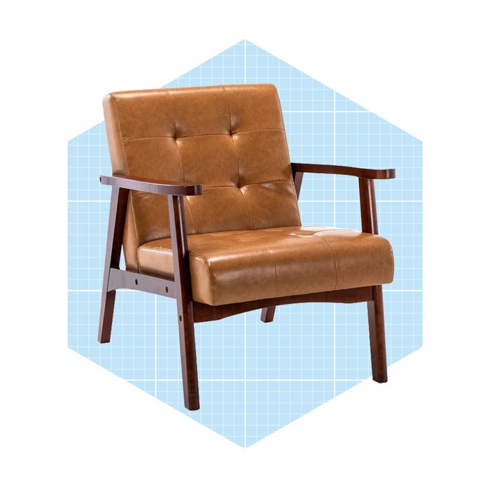 A mid-century modern chair, upholstered in tan leather, rests on a blue grid-patterned background, showcasing its wooden armrests and legs.