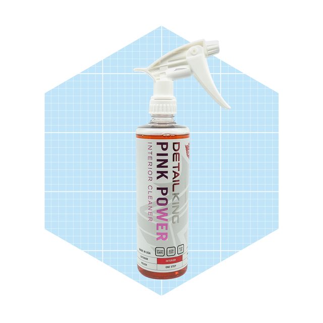 A spray bottle labeled "Detail King Pink Power Interior Cleaner" stands against a light blue geometric background, ready for use in cleaning.