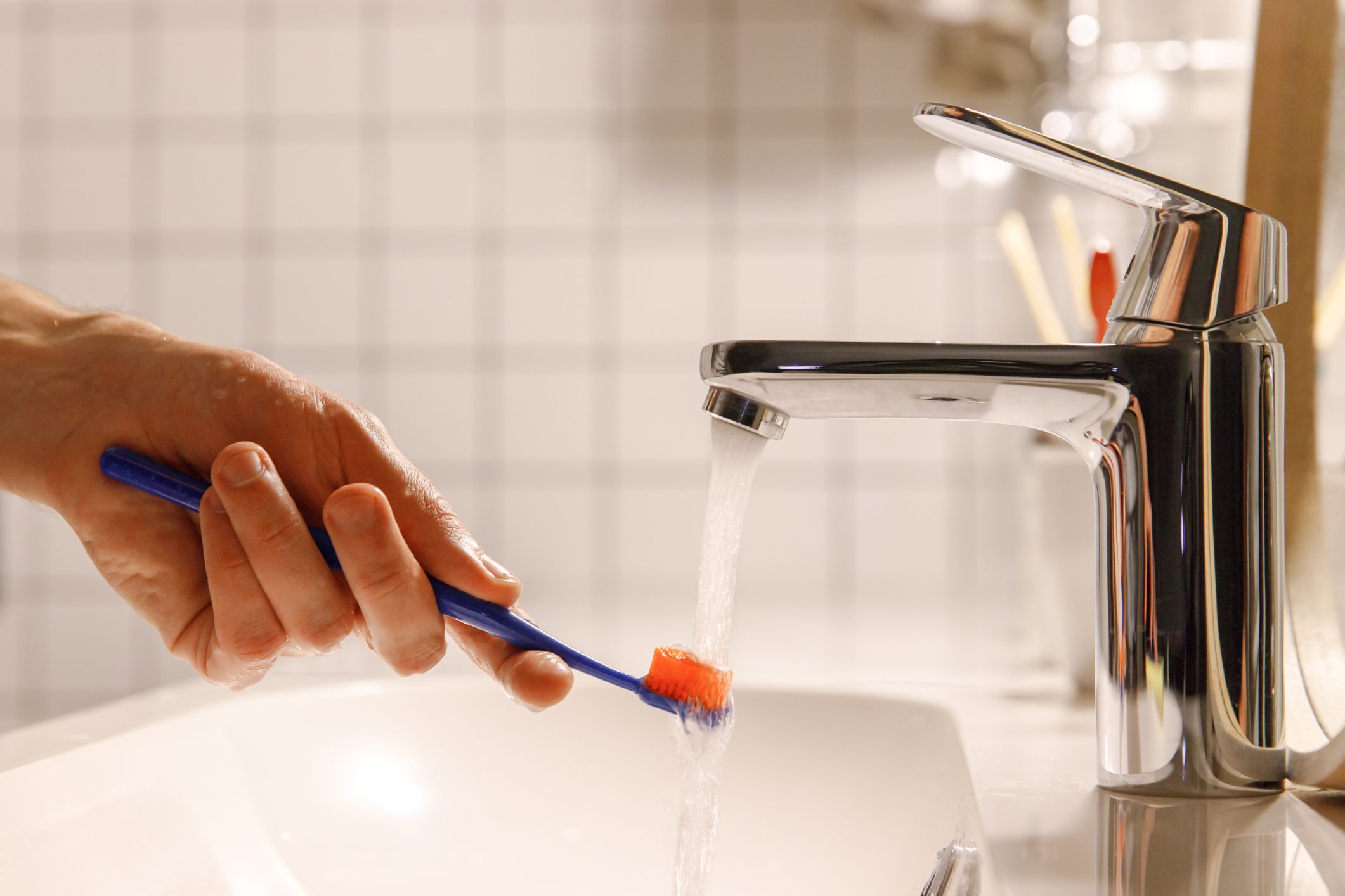 Close-Up Of Hand Holding Faucet In Bathroom