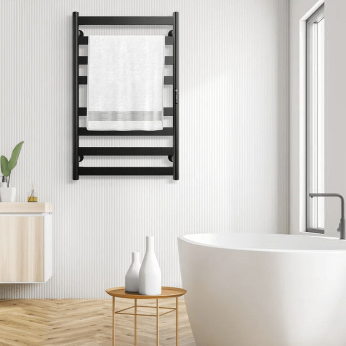 A black towel rack holds a white towel in a modern bathroom, with a bathtub, wooden flooring, and minimalistic decor creating a serene environment.