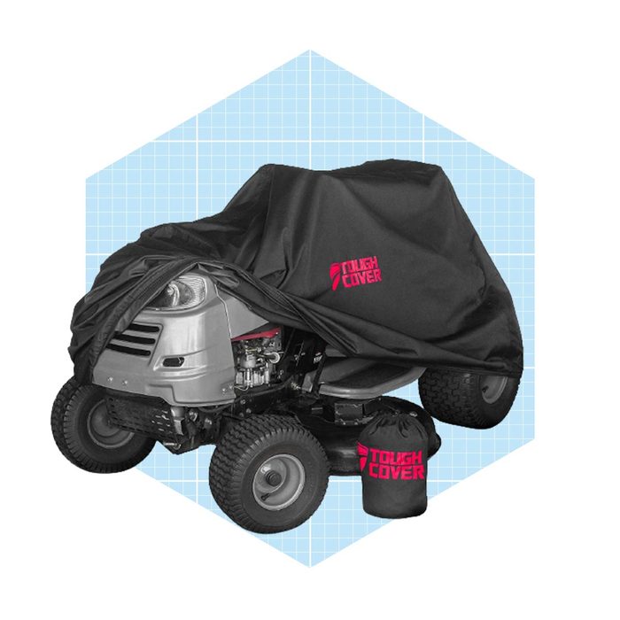 A riding lawn mower is covered with a black protective cover, featuring a logo. A small bag is placed beside it, set against a light blue grid background.