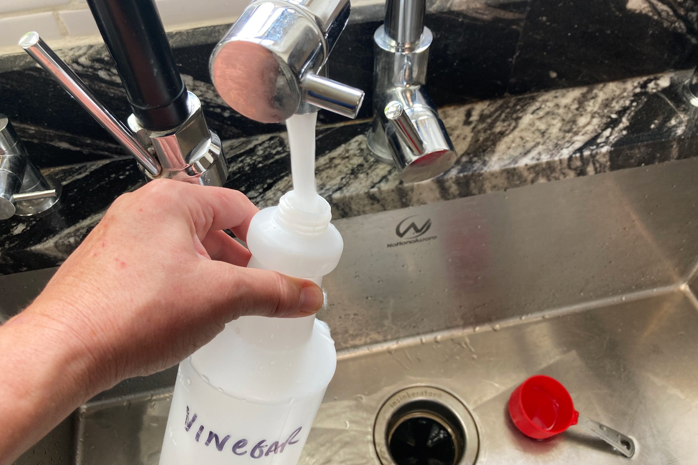 filling spray bottle with water from the sink