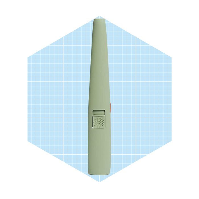 A green, elongated object with a switch lies flat against a light blue grid background, suggesting a tool possibly used for cutting or marking.
