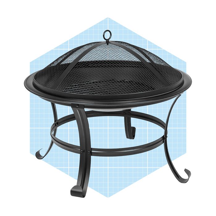 A black metal fire pit rests on curved legs. It features a mesh dome for safety, set against a light blue geometric background.