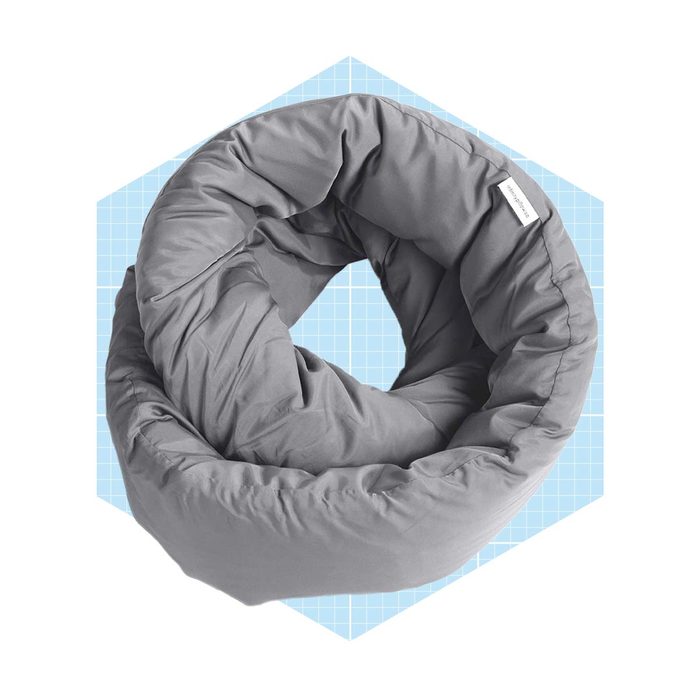 A gray, circular pillow rests on a blue grid background, creating a cozy appearance while suggesting comfort and support for relaxing or sleeping.