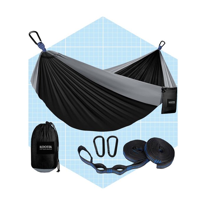 A black and gray hammock hangs between two points, surrounded by carabiners and straps on a blue grid background, suggesting outdoor relaxation equipment.