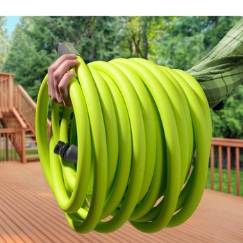 A person holds a coiled, bright green garden hose. The setting features a wooden deck and greenery in the background, indicating an outdoor environment.