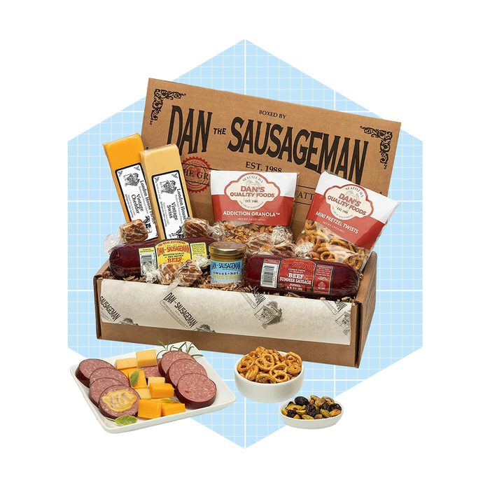 A wooden box contains assorted meats, cheeses, and snacks, while a plate showcases sliced meats and cheeses, set against a light blue backdrop.