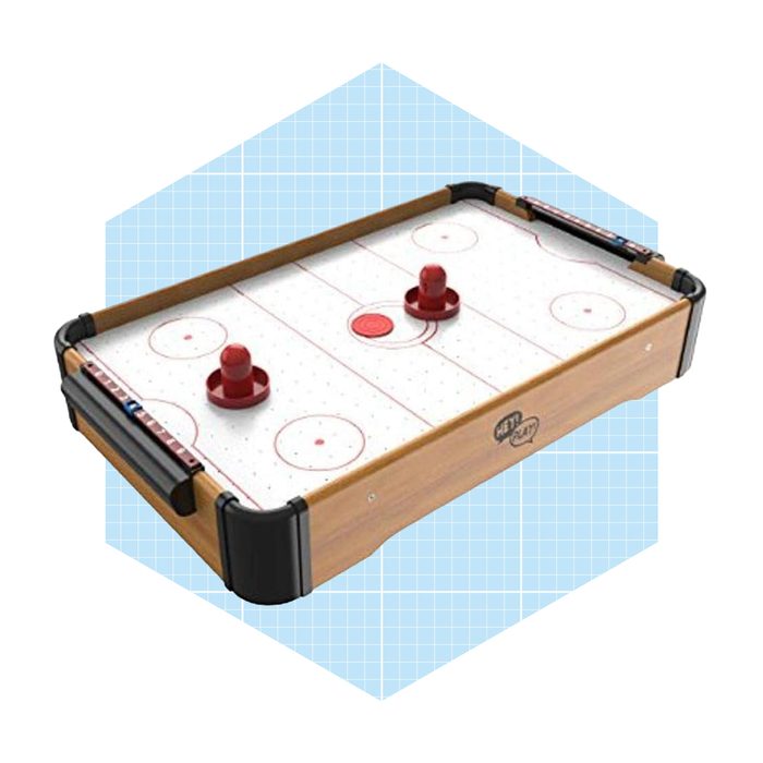 A tabletop air hockey game features a smooth surface with two red paddles and a central puck, set against a light blue geometric background.