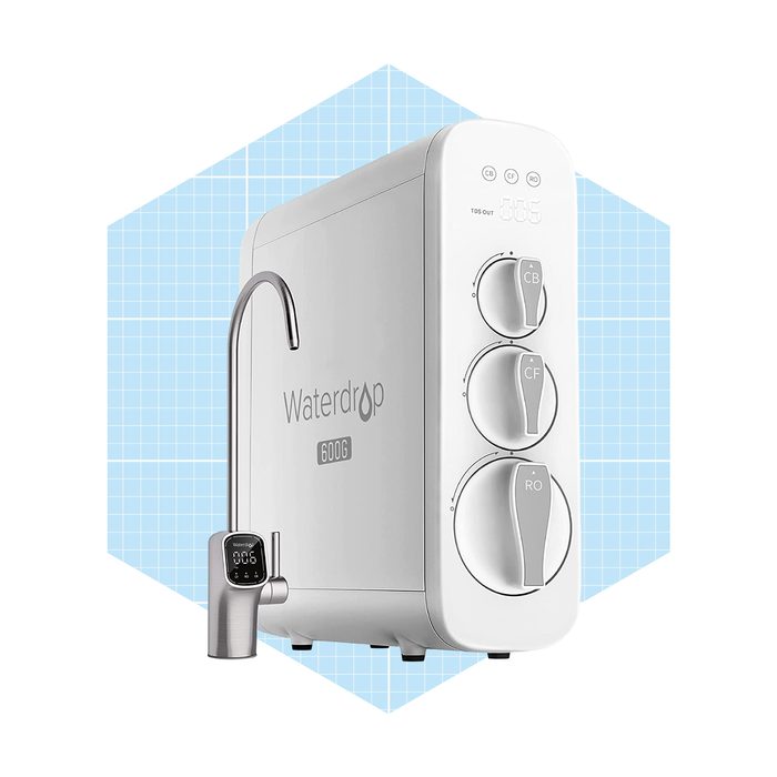 A water filtration system with three control knobs dispenses purified water through a curved faucet. The background has a light blue grid pattern.