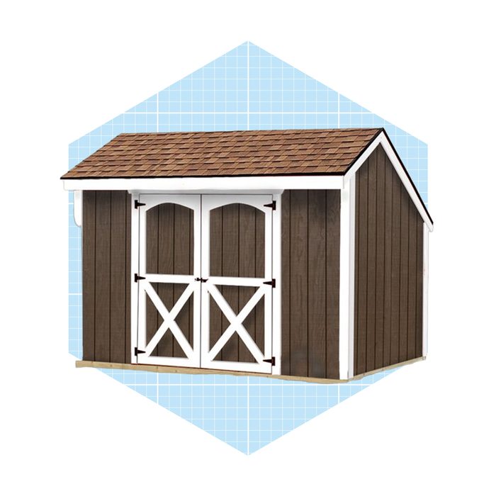 A wooden storage shed with a brown exterior and white trim stands against a blue grid background, featuring double doors with arched tops.