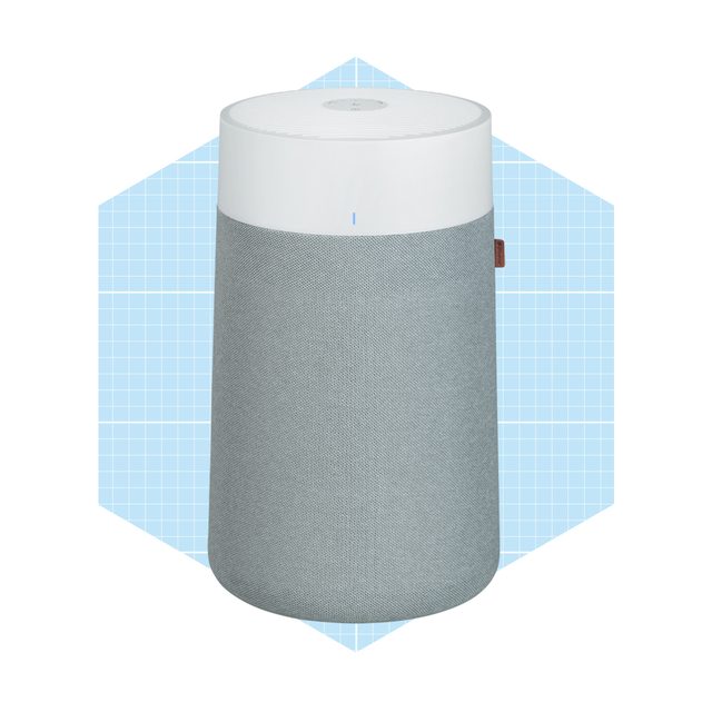 A cylindrical smart speaker with a gray fabric exterior and white top sits against a light blue geometric background, designed for audio playback.