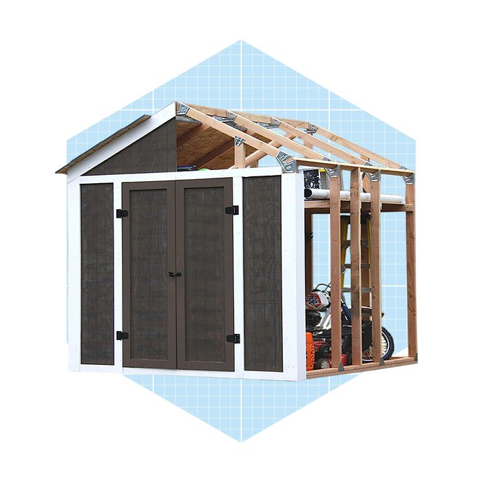 A partially constructed garden shed stands upright, featuring wooden frames and mesh doors, set against a light blue geometric background.