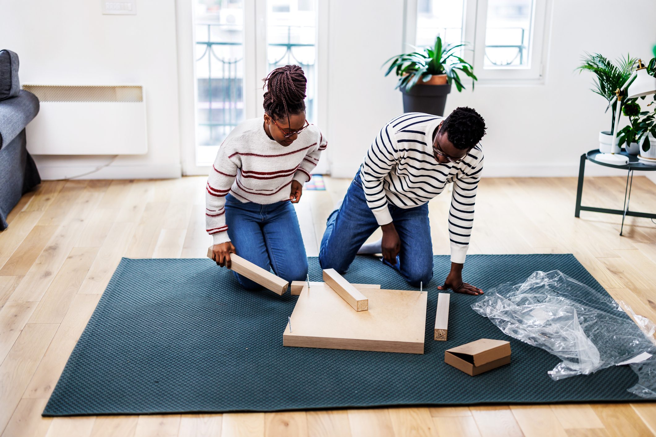 A young African couple is enjoying assembling a wooden table in the new house.