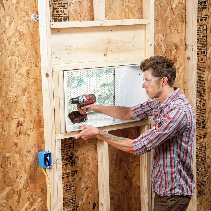 A Man Fixing Through The Wall AC in Garage with Drill