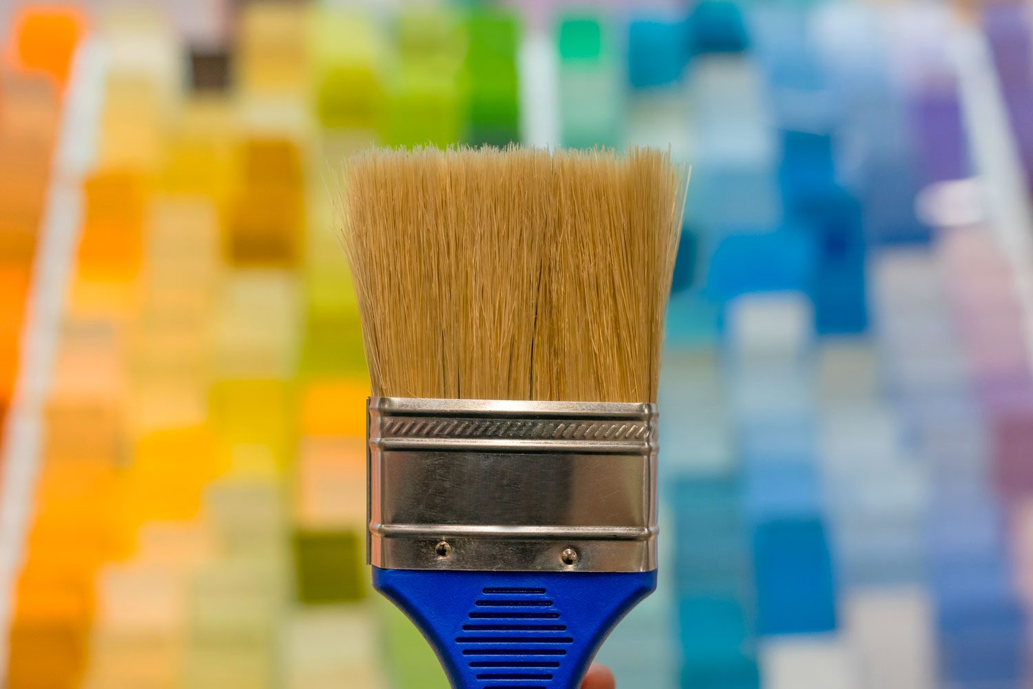 Close-up on a paint brush with color samples at the background at a home improvement store