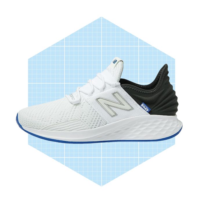 A white athletic shoe with a dark green heel, positioned against a light blue grid background, appears ready for performance or casual wear.