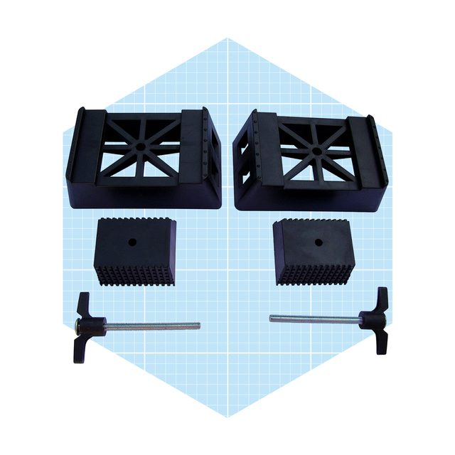 Four black rubber blocks and a metal screw clamp are arranged on a light blue grid background, suggesting tools for stabilization or support.