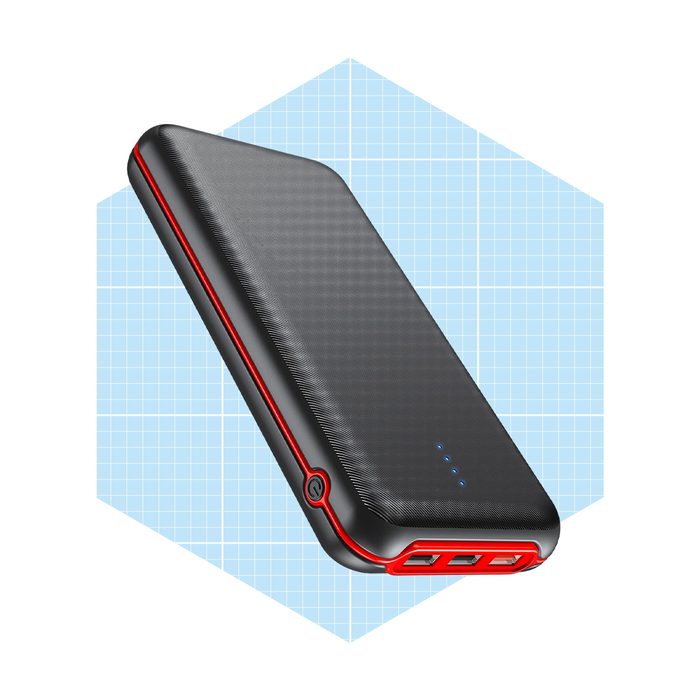 A black and red power bank rests at an angle, displaying charging ports and indicator lights, set against a light blue grid background.