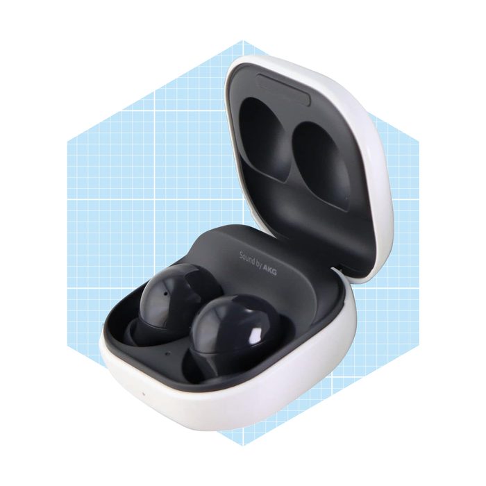Wireless earbuds are housed in an open charging case, displaying a sleek design against a light blue geometric backdrop.