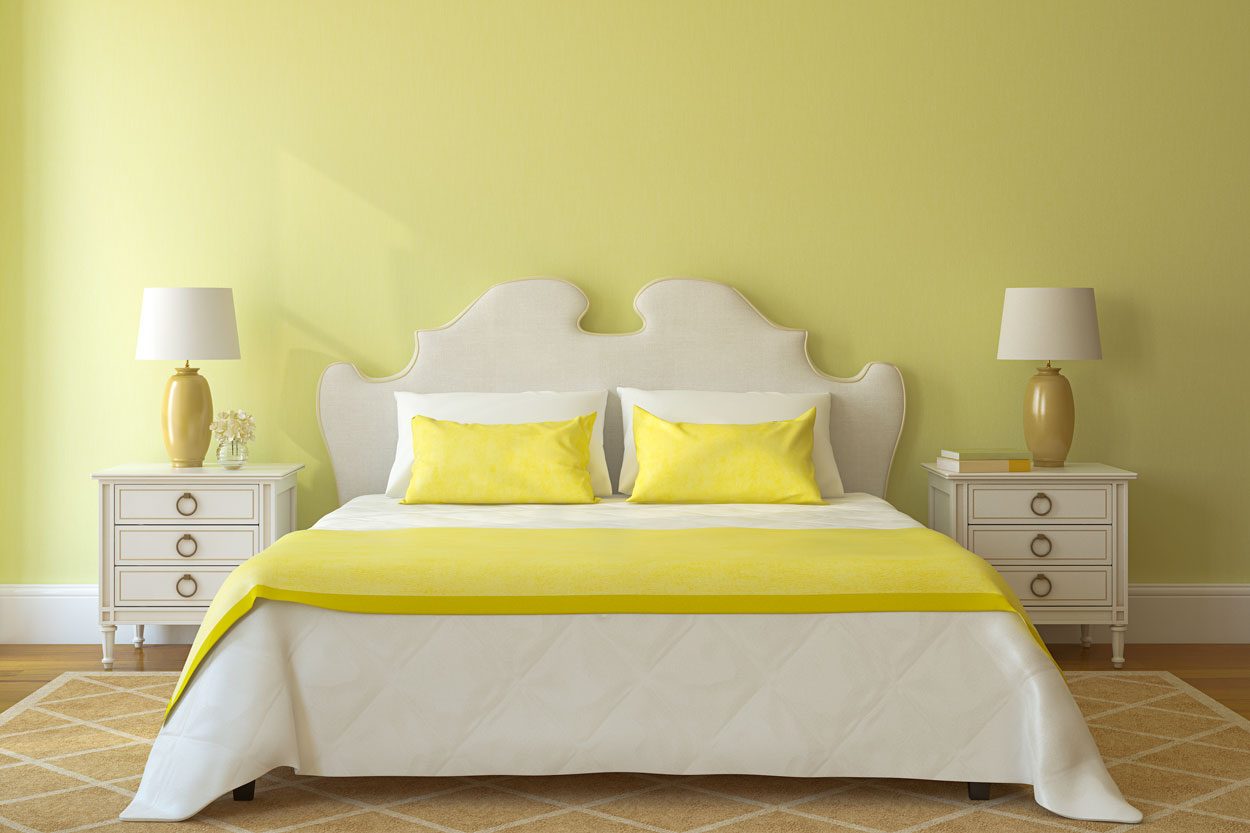 Yellow Bedroom Interior with Bed, Nightstands, Lamps and Complete Bedding with light hardwood floors and a rug