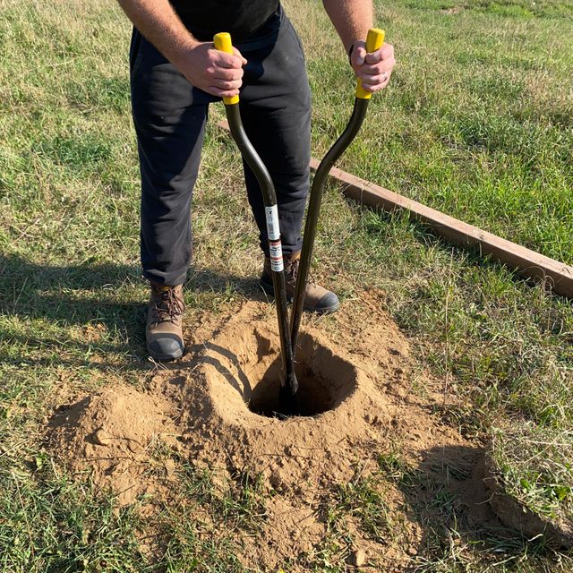 cleaning hole using a hand-operated clamshell post hole digger.