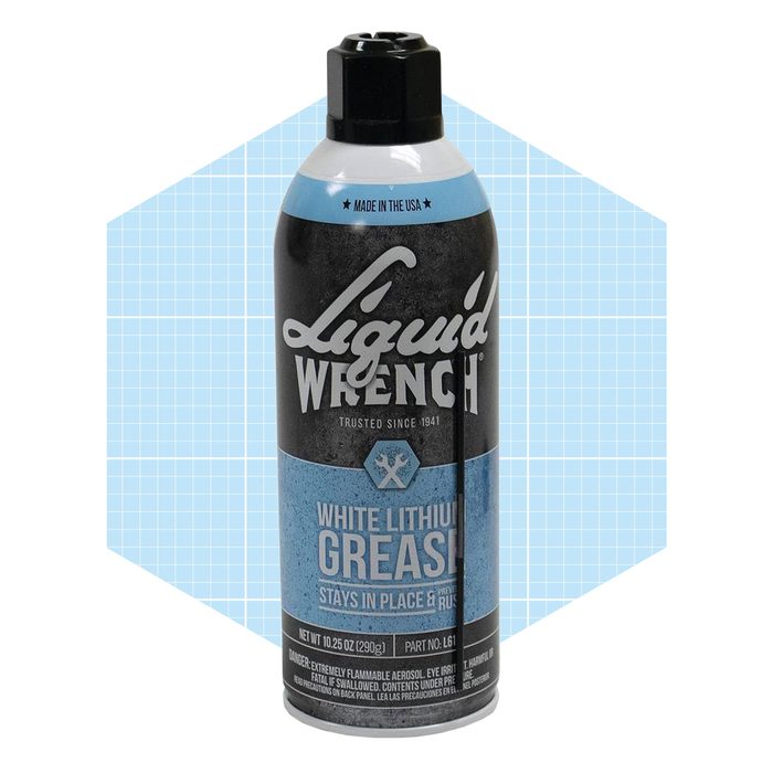 A spray can of Liquid Wrench white lithium grease stands upright against a light blue geometric background, indicating its purpose for lubrication and rust prevention.