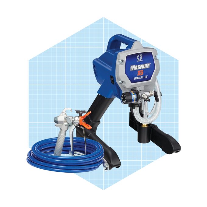 A blue paint sprayer is positioned upright, with a hose coiled beside it. It’s designed for efficient application, likely in construction or DIY projects.