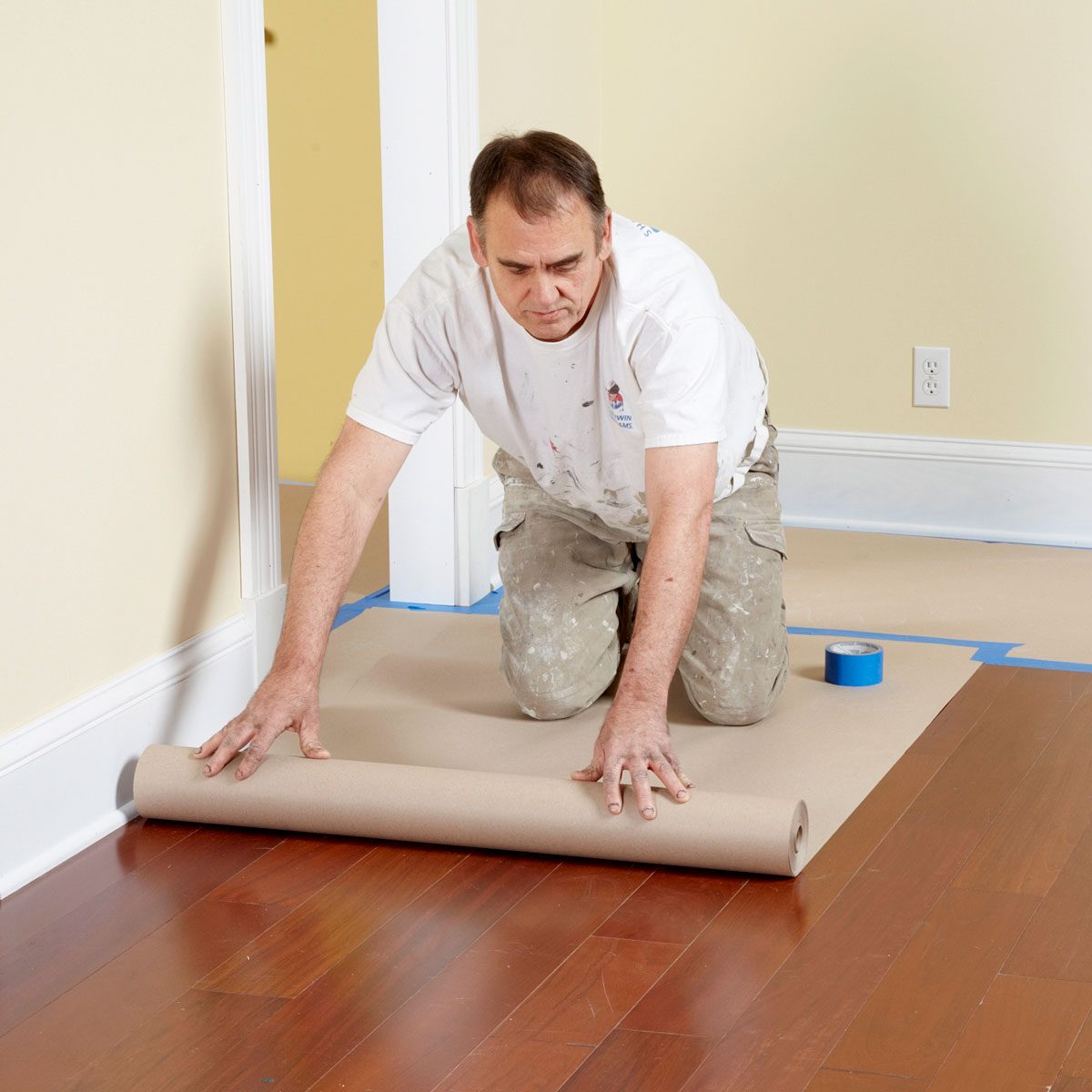 A Man Laying Drop Cloth on Floor