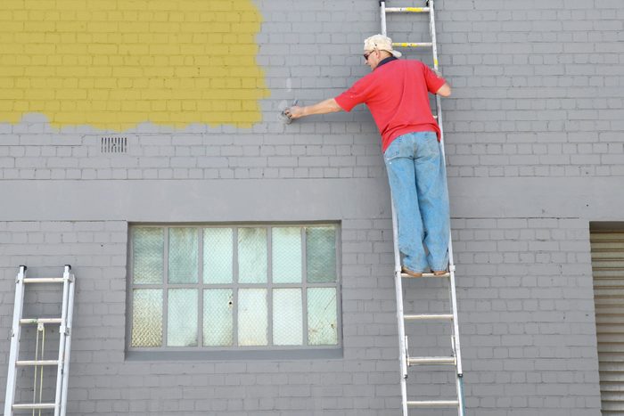 Man On Ladder Painting Building Exterior