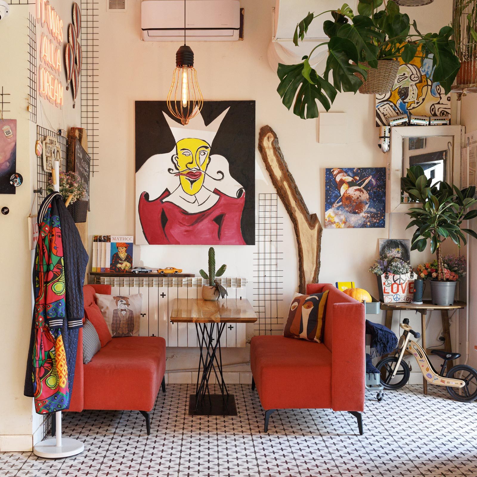 eclectic interior design dining room with two red couches around a table and lots of art on the walls