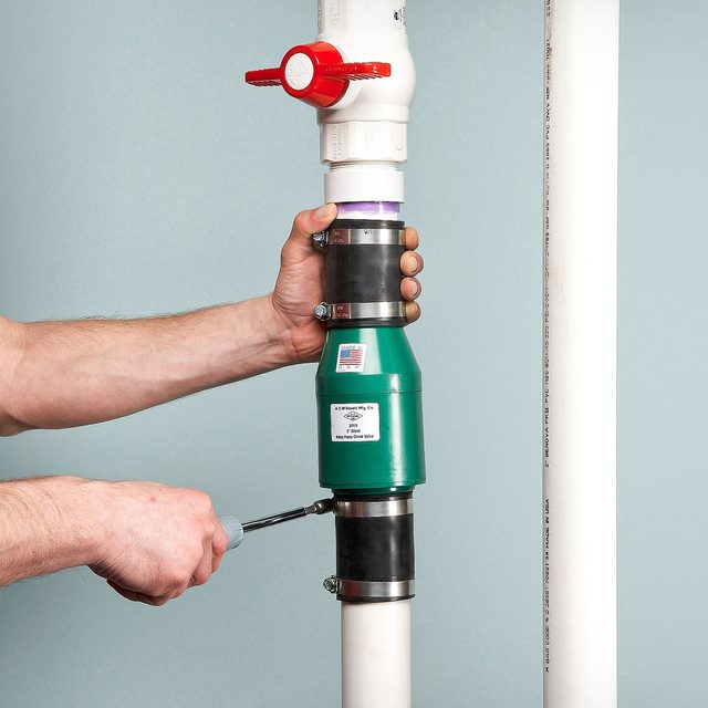 Someone Installing A Sump Pump Check Valve