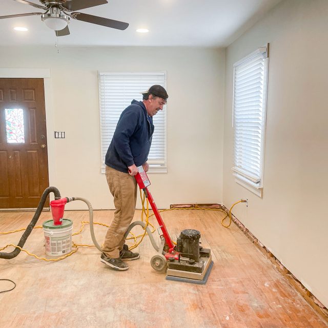 A Person Sanding Hardwood Floor with Floor Sanding Machine