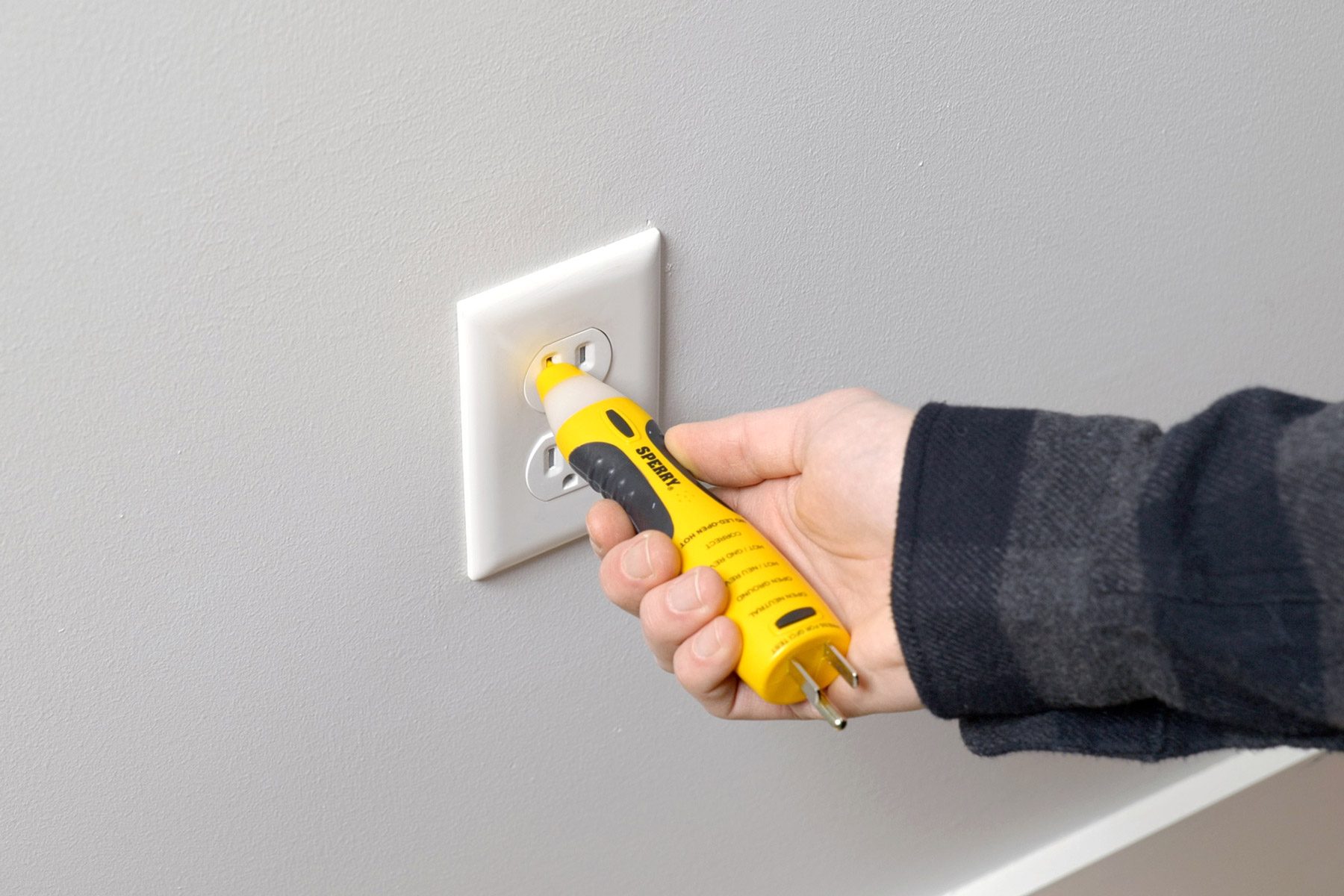 A hand holding a yellow electrical device