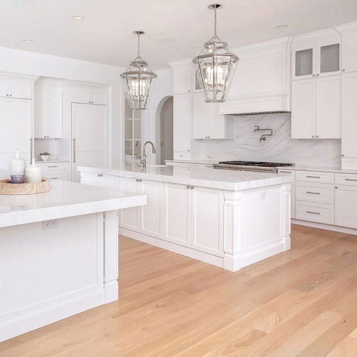 A kitchen space with white walls and white counters with wooden furniture