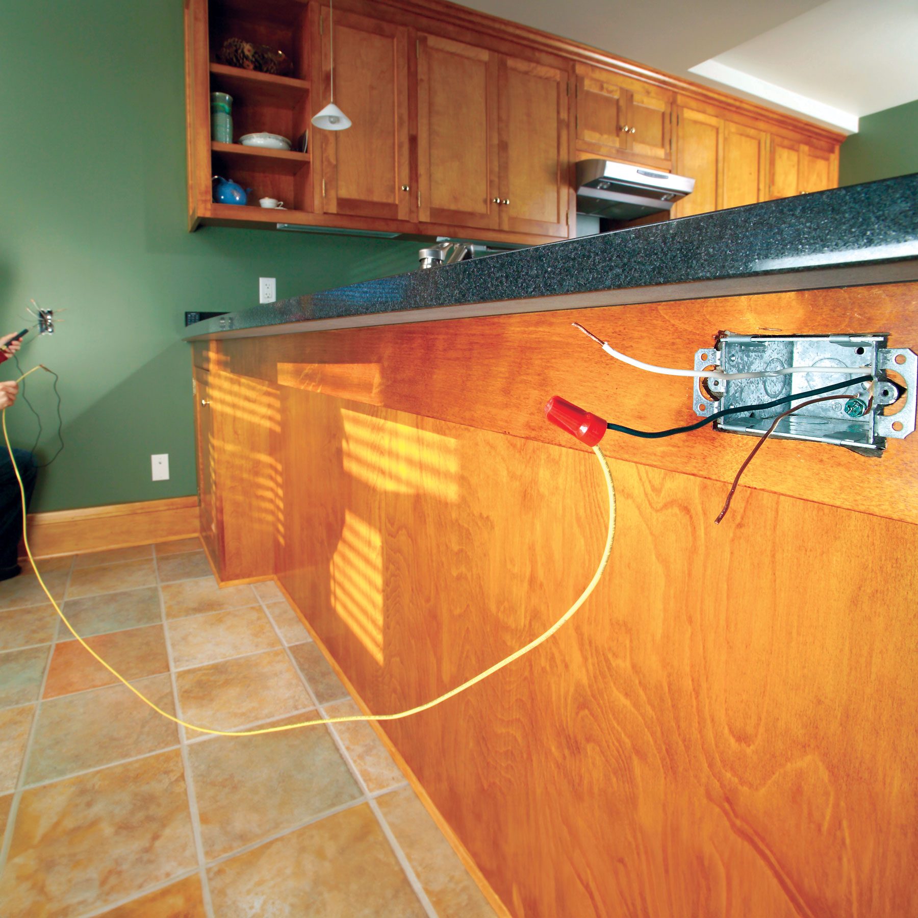 A test wire is being used to identify circuit wires that run between a pair of electrical boxes.