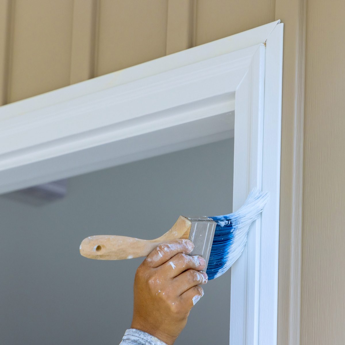 A hand holding a brush can be seen painting the trim.