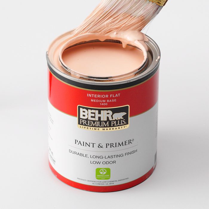 Can of paint with a brush dipped in paint on top.